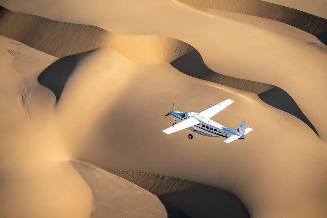 Cessna 208 von Wilderness Air über den Dünen der Namib