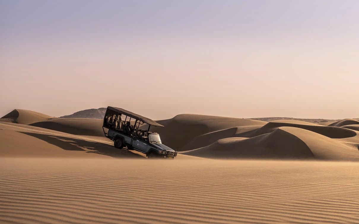 Safarifahrzeug auf einer Düne nahe der Serra Cafema Lodge