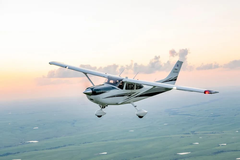 Single engine piston aircraft in flight above wooded terrain