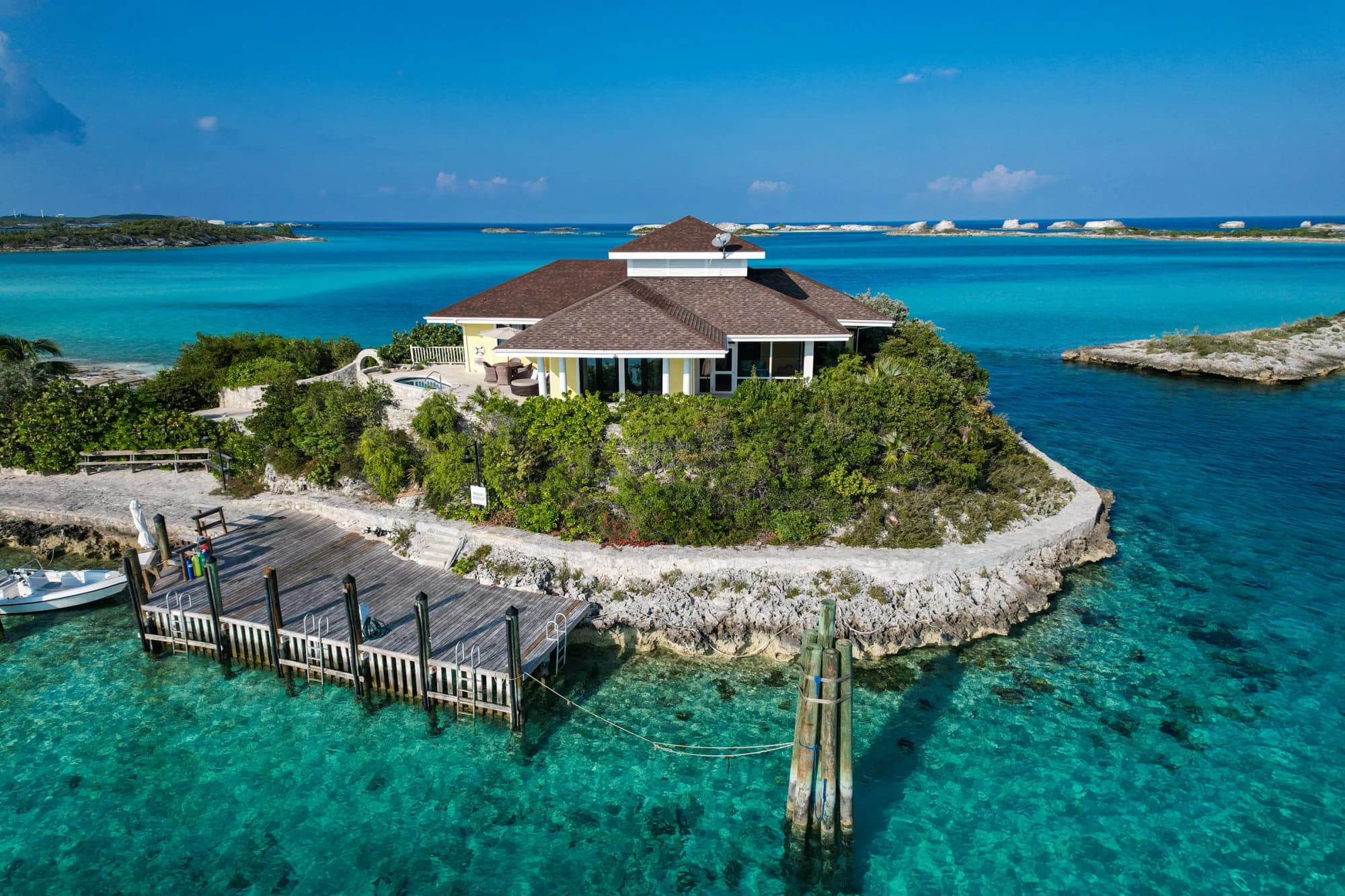 Eine Villa des Fowl Cay Private Island Resort auf der Landzunge, davor der eigene Steg im türkisen Wasser