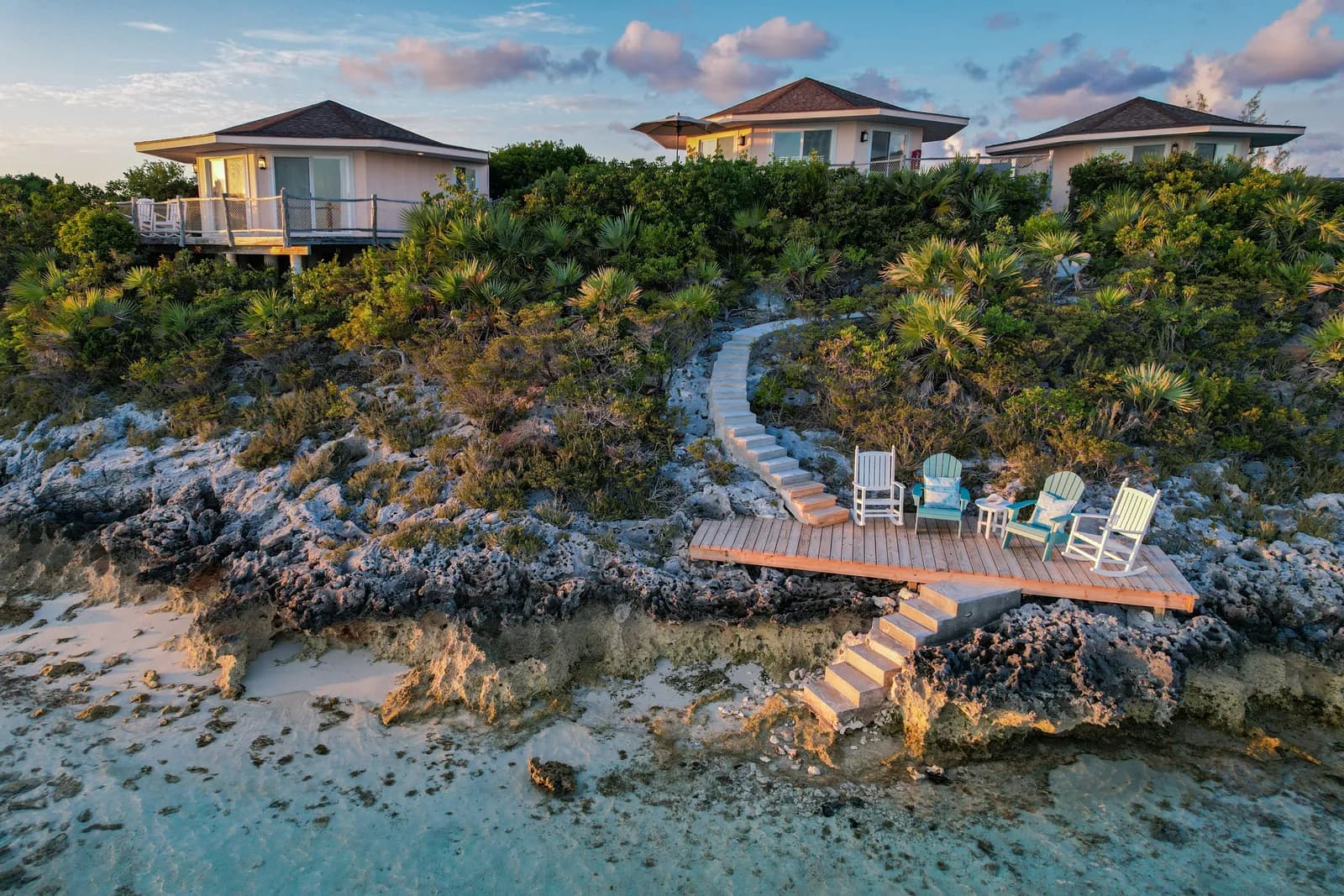 Villen des Fowl Cay Resort über dem Wasser, davor ein Holzdeck mit Stühlen