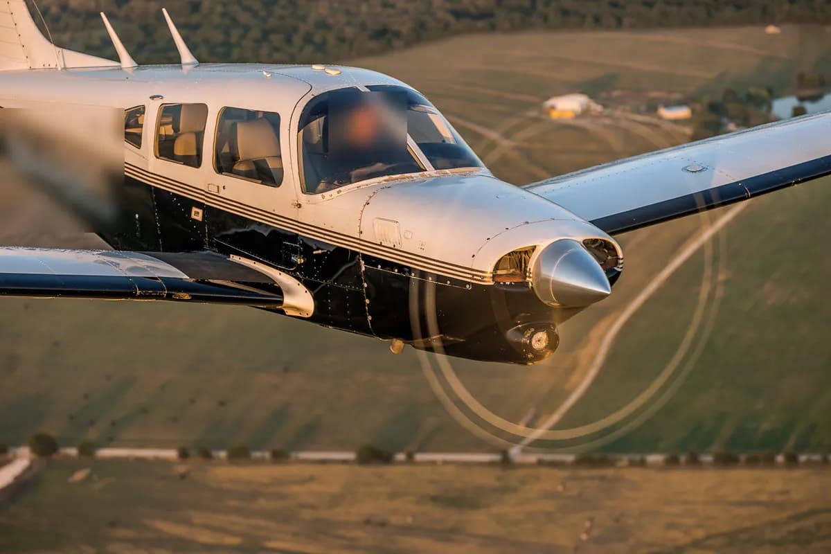 Piper PA-28 in flight over fields in the evening light