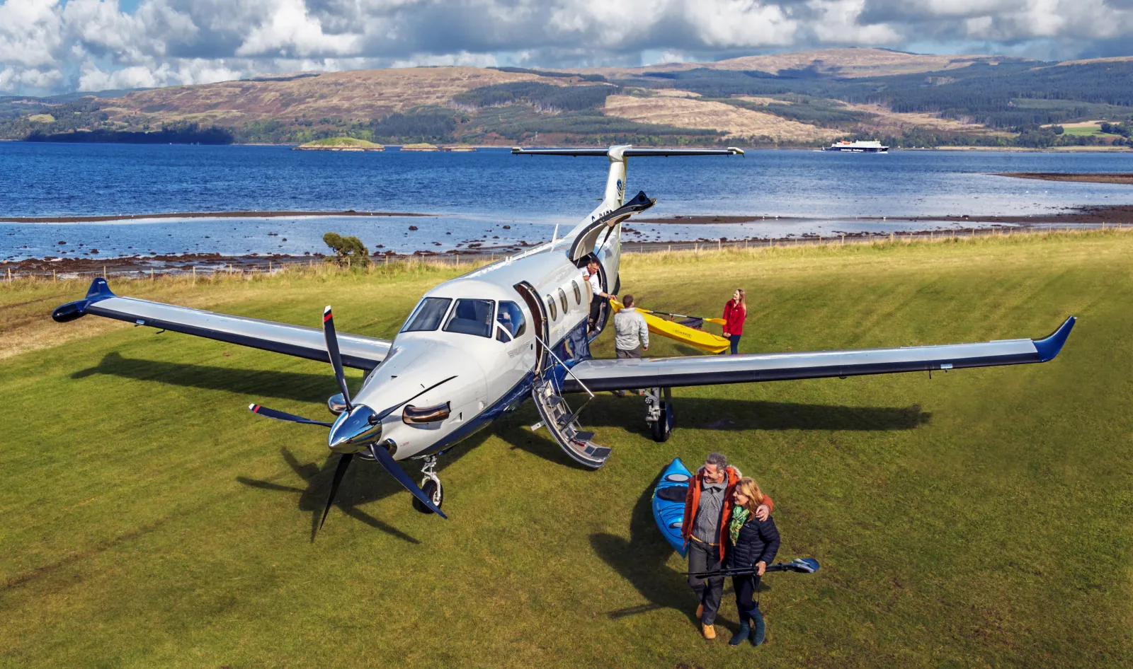 Pilatus PC-12 NGX mit geöffneter Tür auf einer Graspiste am Meer